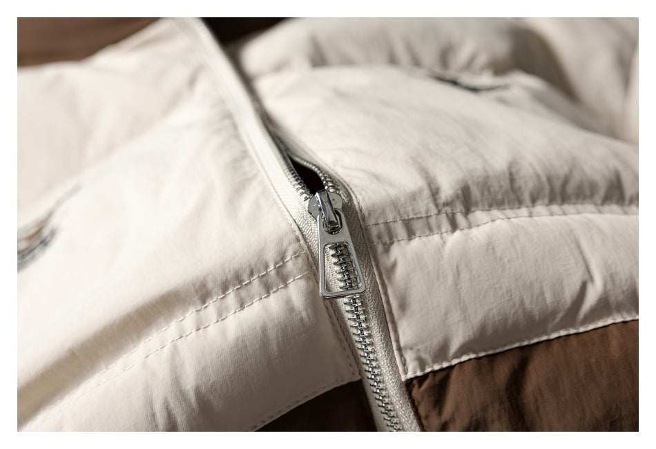 Close-up of the open silver zipper and cream panels on a brown and cream jacket.