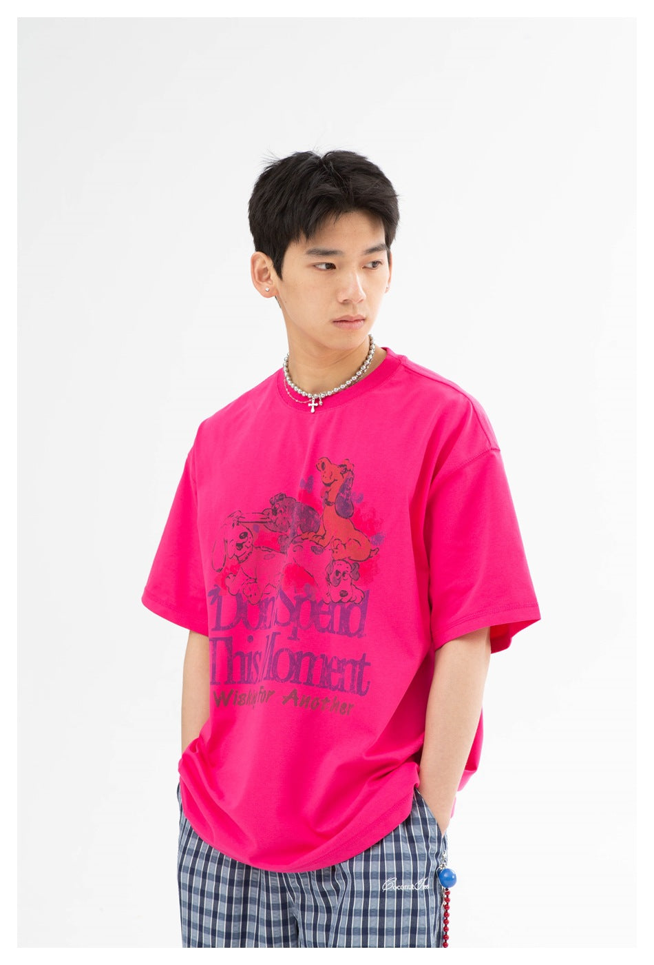Model wearing a hot-pink graphic T-shirt with an illustrated animal print and blue plaid trousers.