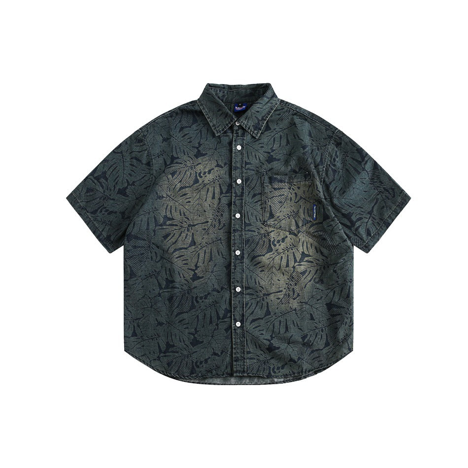 Blue-green short-sleeve button-up shirt with an allover leaf print, chest pocket and faded center, flat lay front view
