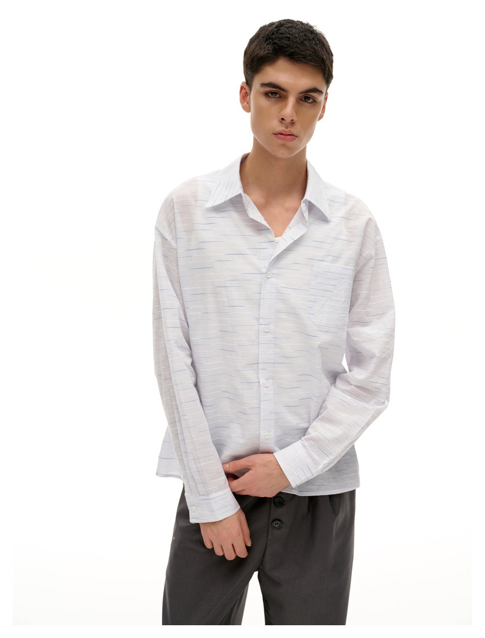 Model wearing a white long-sleeve button-up shirt with fine blue horizontal stripes and a chest pocket.