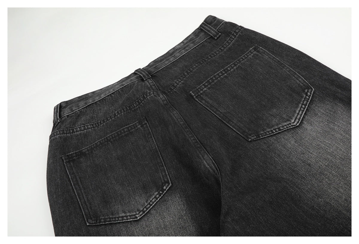 Angled partial back view of charcoal-black jeans, showing the waistband, belt loops, yoke, and two back pockets.