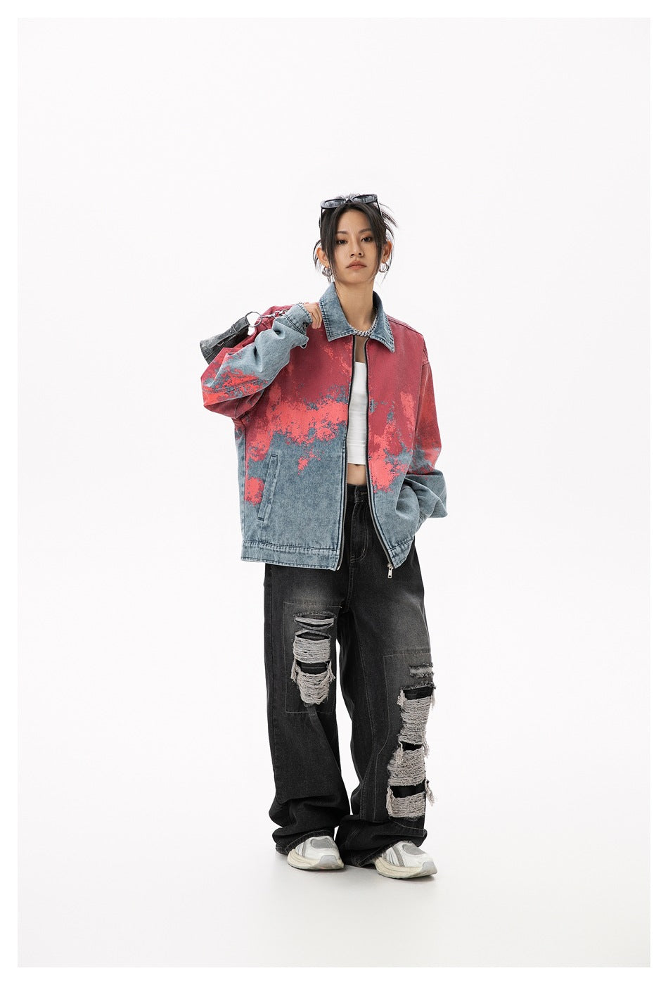 Model in the red-splatter blue denim jacket with a bag over one shoulder, white top and ripped black jeans