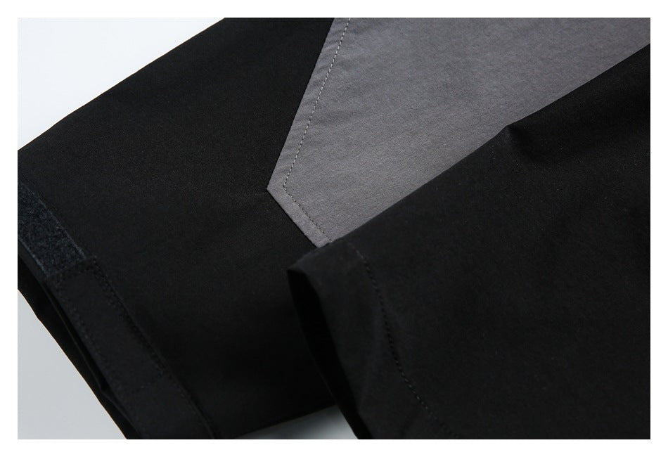 Close-up of a charcoal-gray angular panel stitched onto a black garment, with a hook-and-loop tab at the edge.