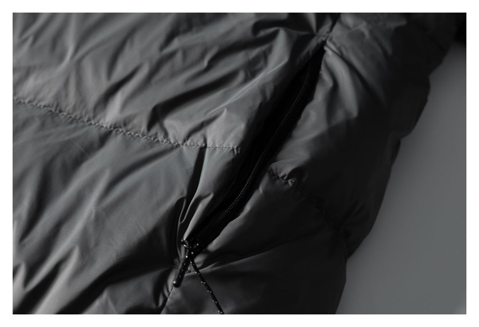 Angled detail of a black zippered pocket and stitching on a dark gray jacket.