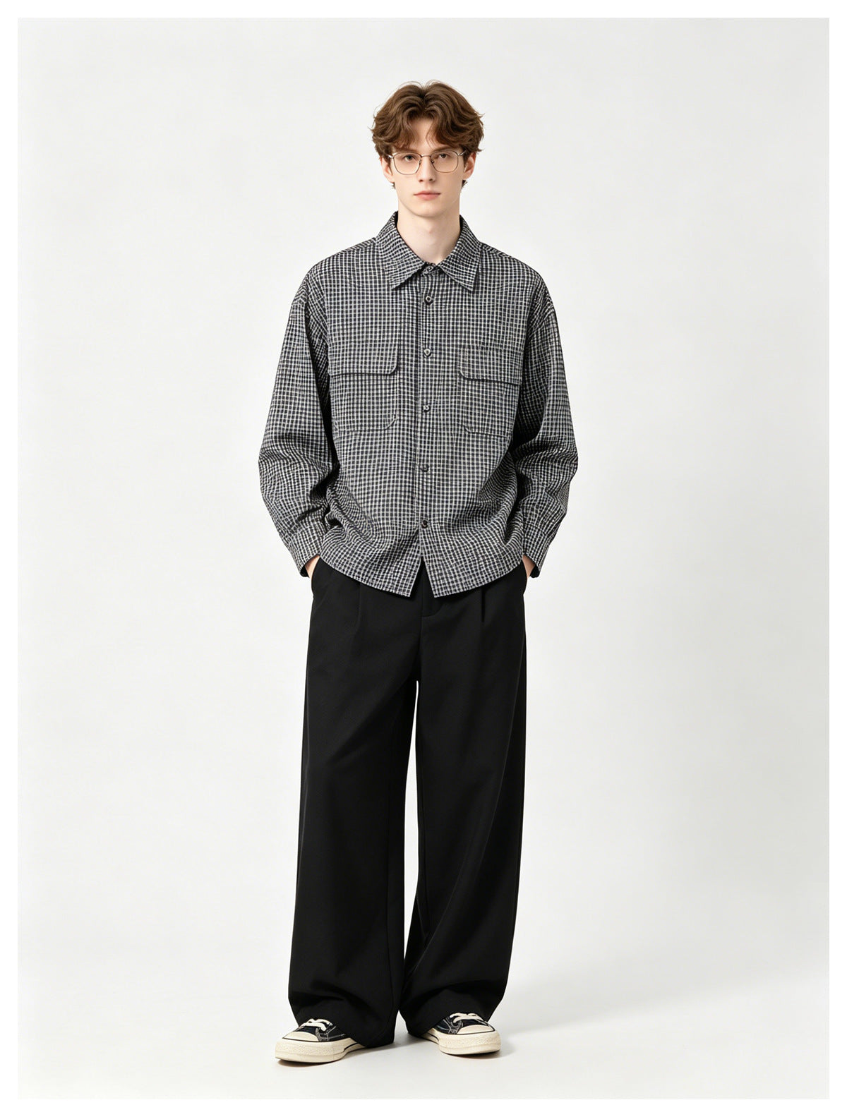 Model wearing a dark checked button-up shirt with two chest pockets and loose black trousers.