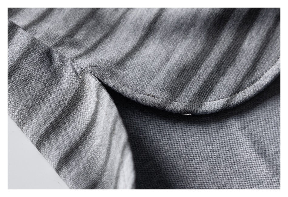 Close-up of gray striped fabric with a curved stitched seam and finished edge.