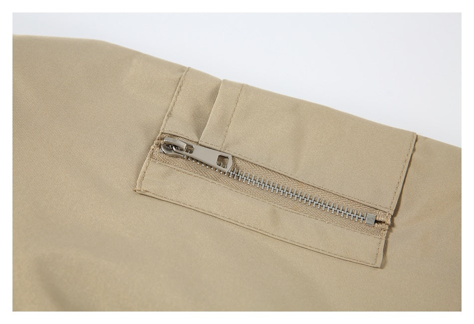 Close-up of a beige jacket's zippered pocket and stitching.