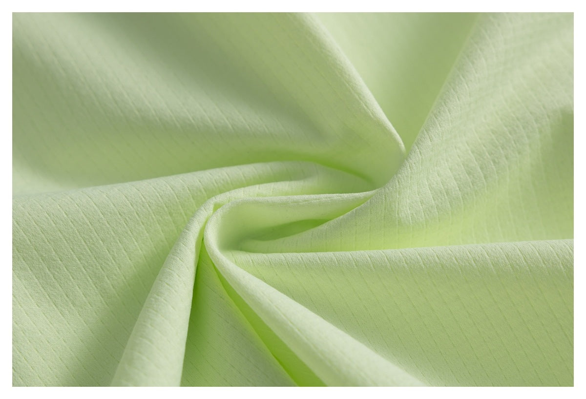 Close-up of pale lime fabric draped into soft folds, showing its subtle texture.
