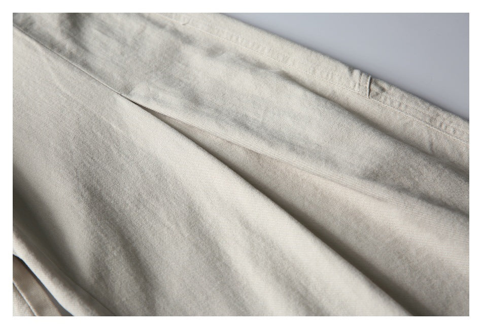 Close-up of light beige trouser fabric and a folded seam.
