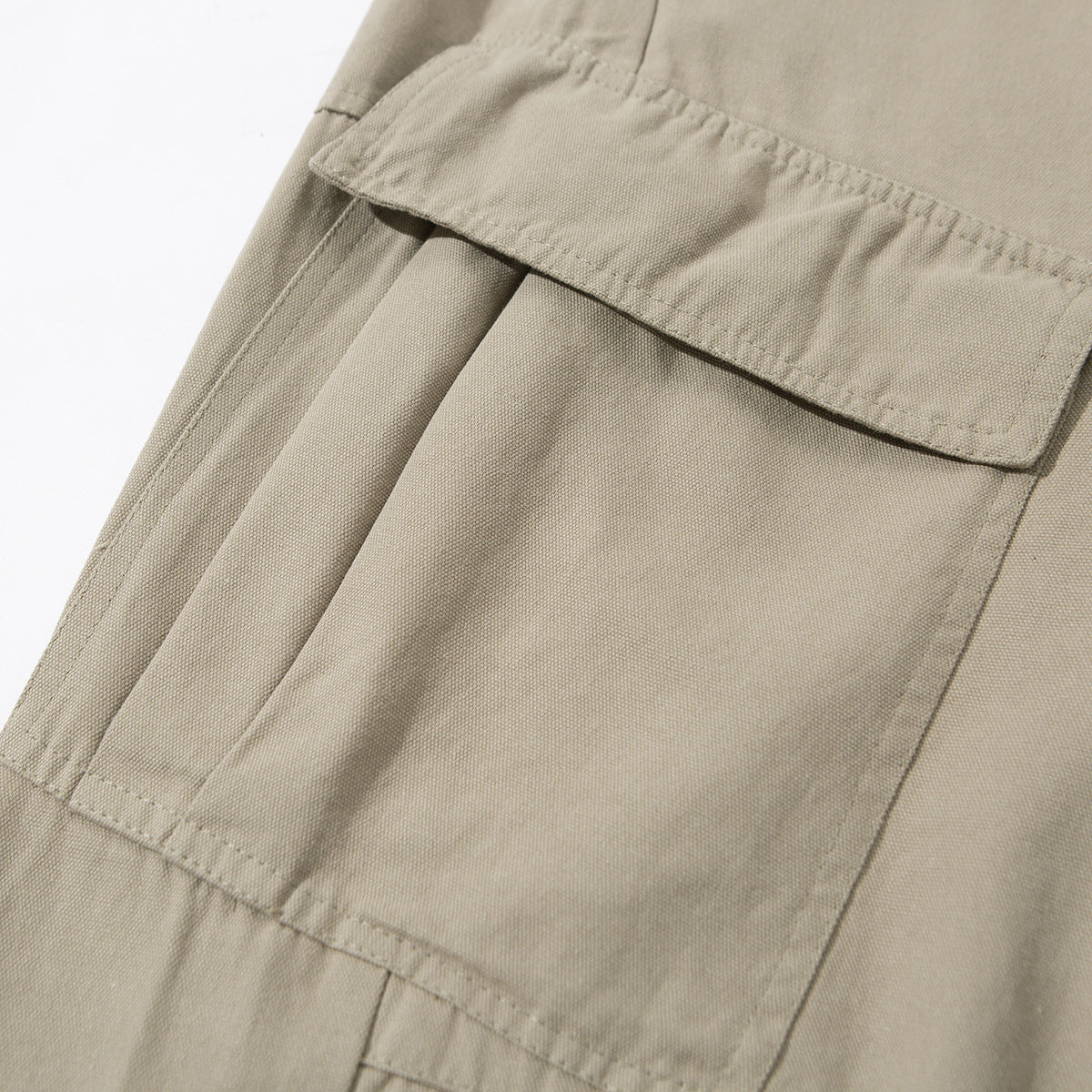Close-up of beige cargo pants with a large flap pocket and visible stitching.