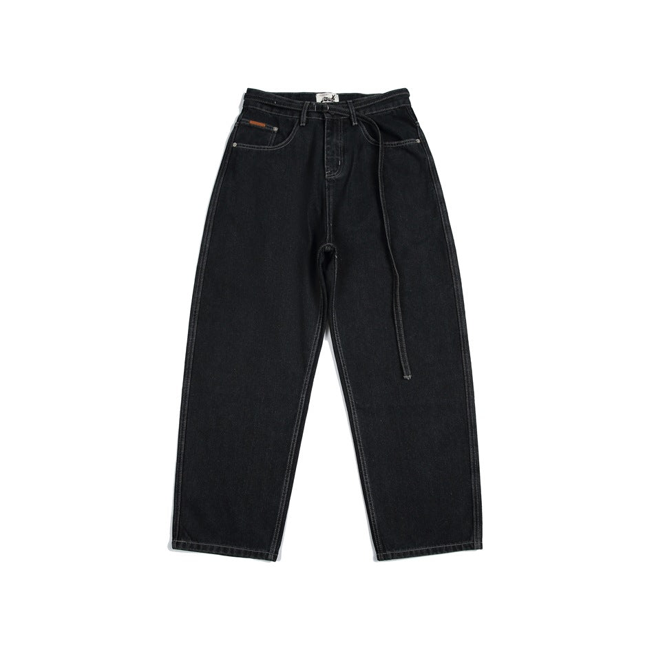 Front view of black wide-leg jeans with front pockets, contrast stitching and a long matching belt.