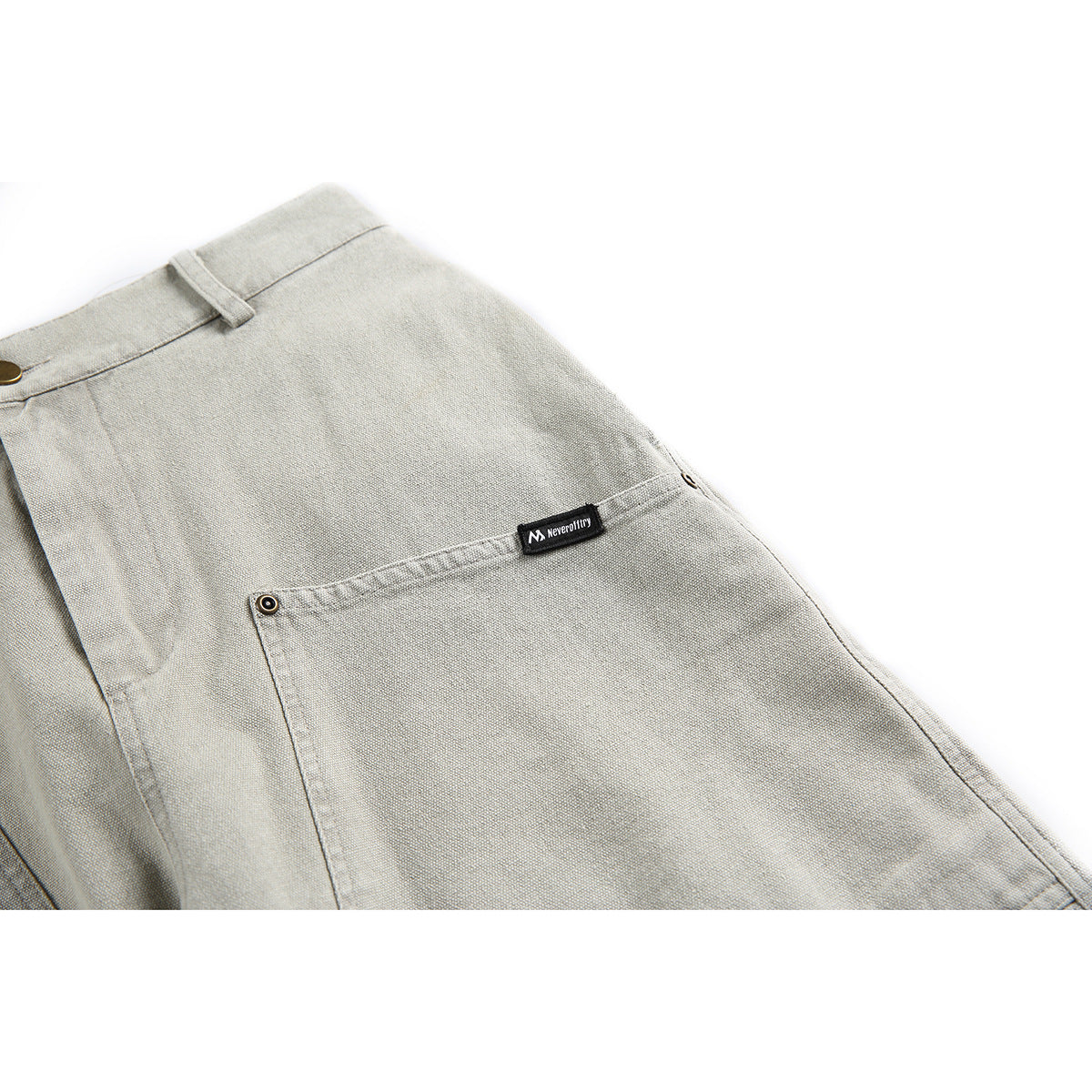 Close-up of a back pocket and small sewn label on light gray shorts.