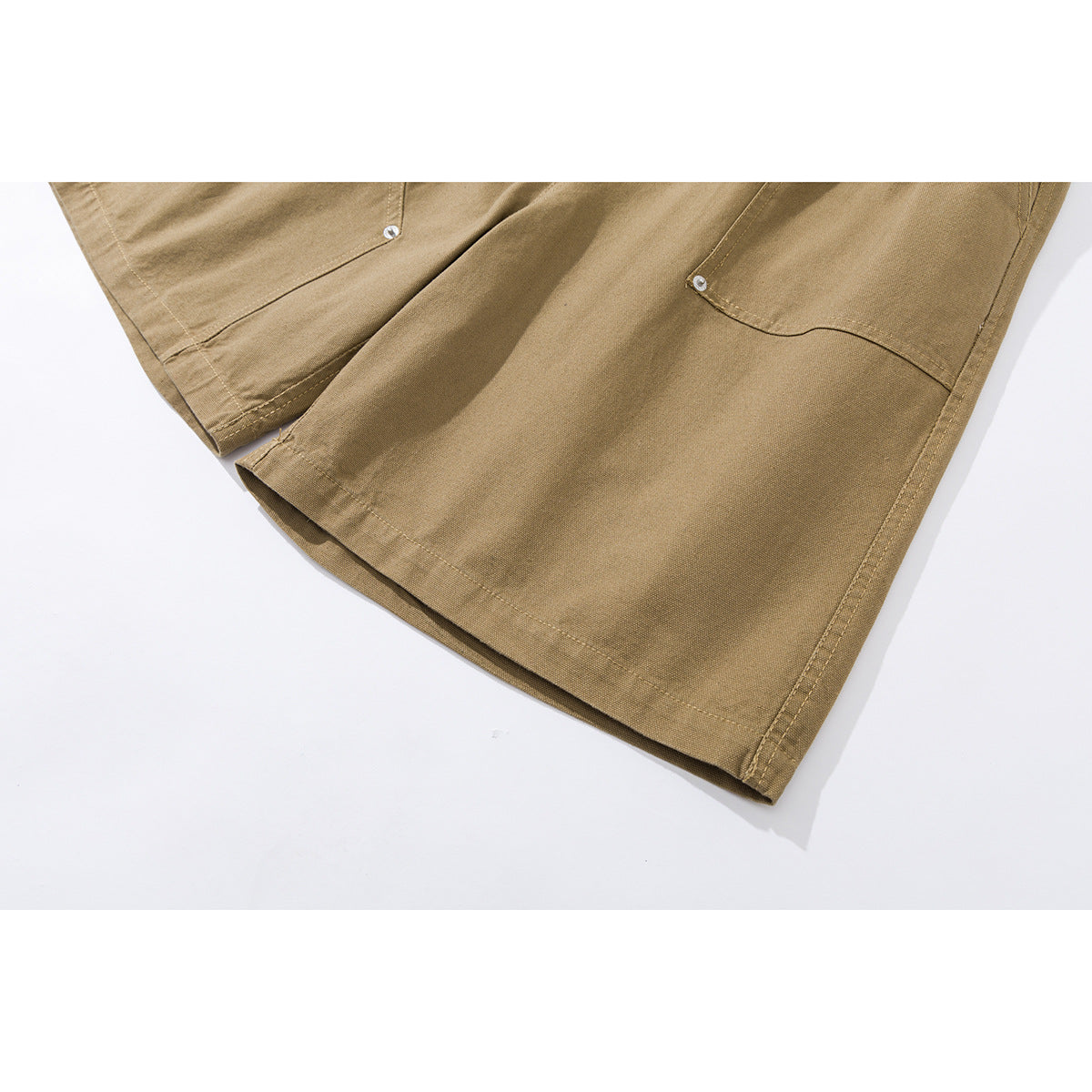 Close-up of tan shorts showing the legs, stitched hems, and front pocket details.