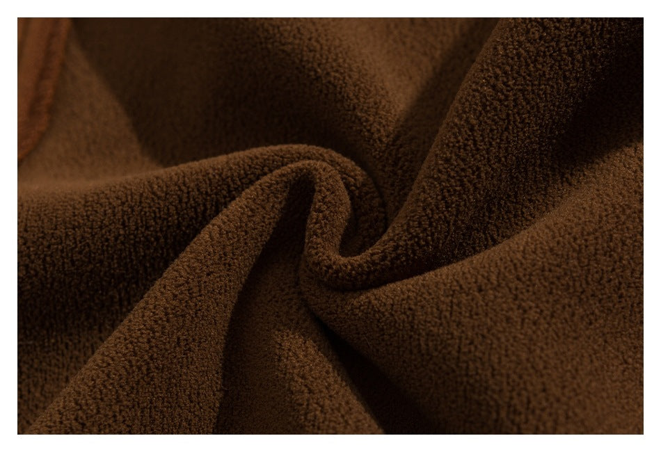 Close-up of dark brown fabric with a dense, soft-looking textured surface arranged in folds.