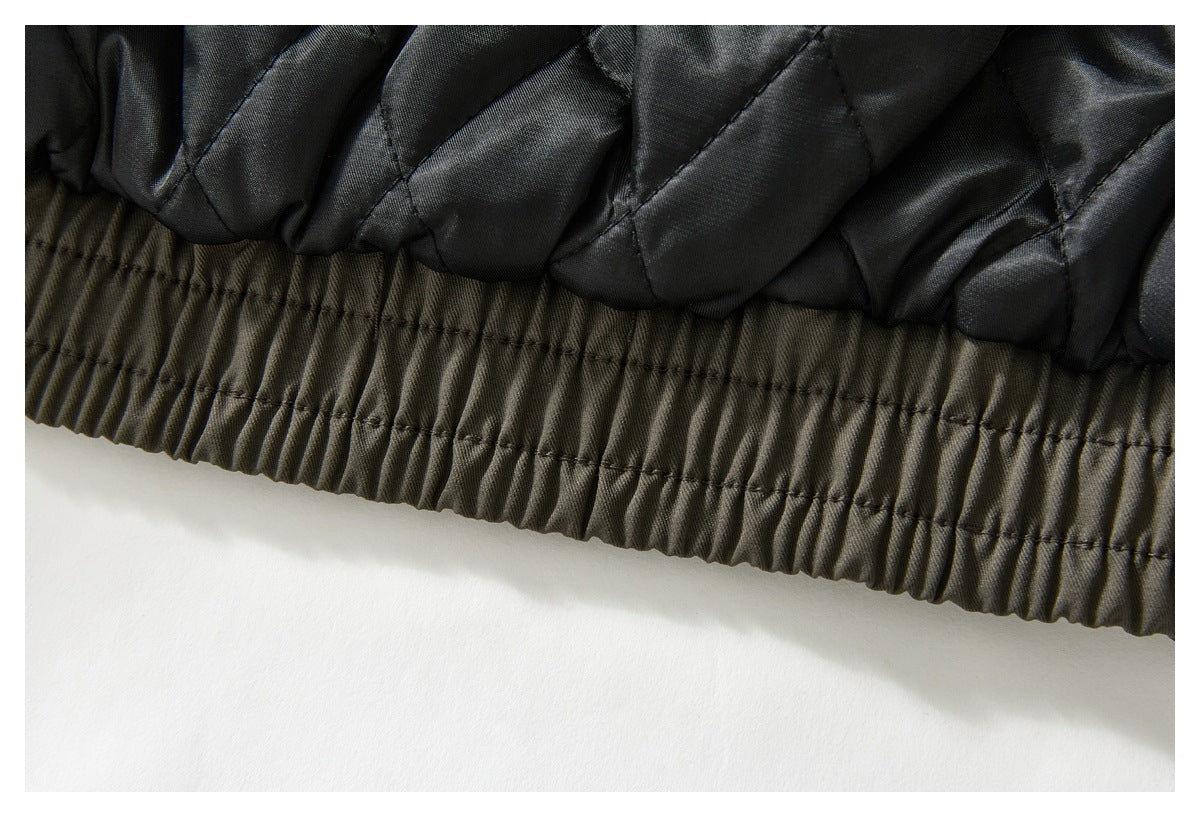 Close-up of black quilted lining joined to an olive-gray garment with a gathered elastic edge.
