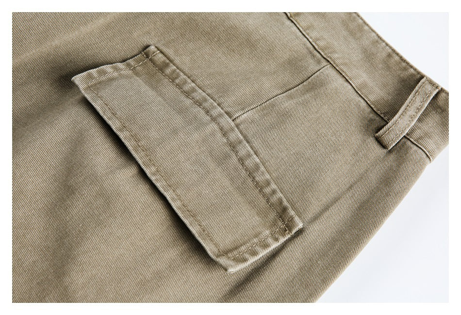 Close-up of a flap pocket and belt loop on khaki trousers.