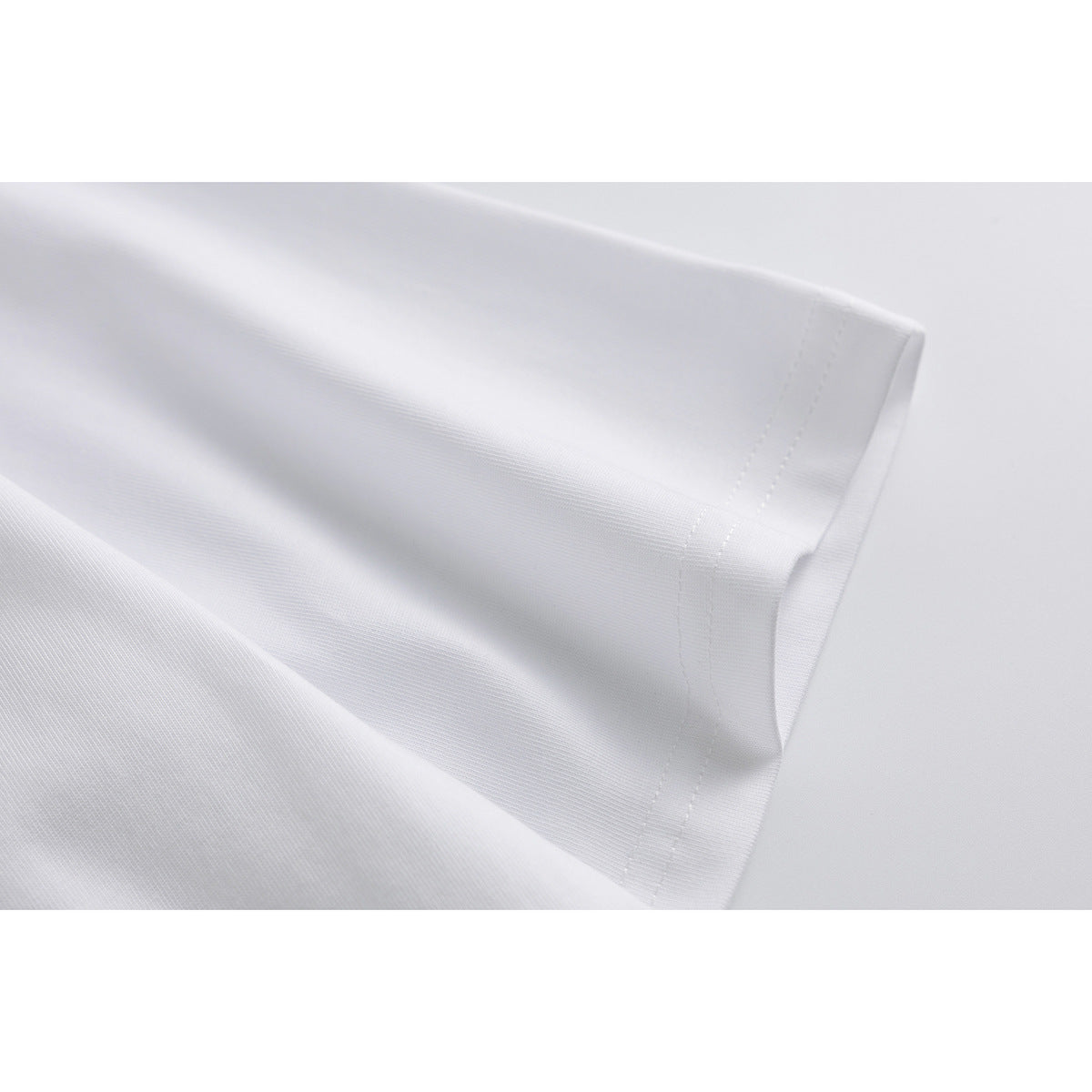Close-up of the white T-shirt's short sleeve hem and stitching.