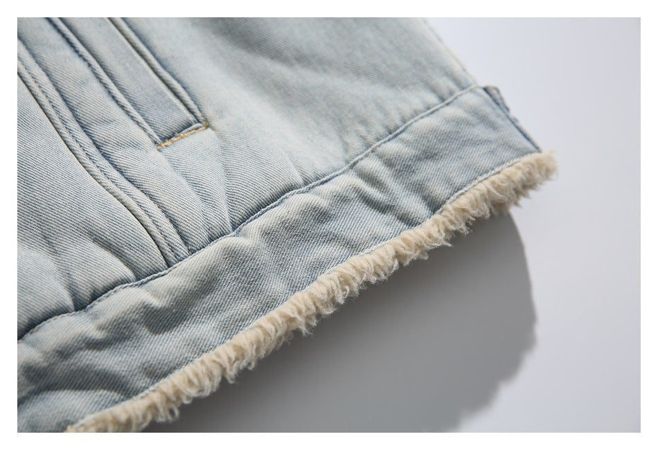 Close-up of the light-wash denim jacket's lower hem, showing cream fringe and a stitched pocket edge.