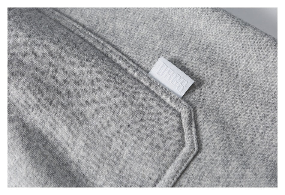Close-up of a gray pants pocket seam with a small white embossed logo tab.