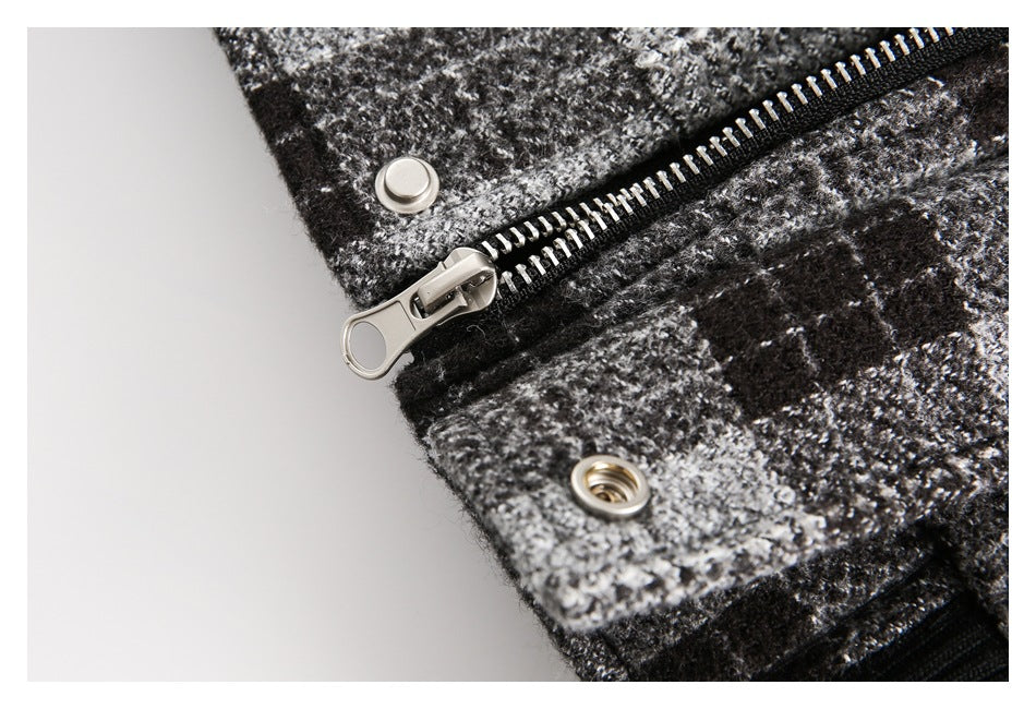Close-up of a metal zipper and snap fasteners on a black-and-gray plaid garment.