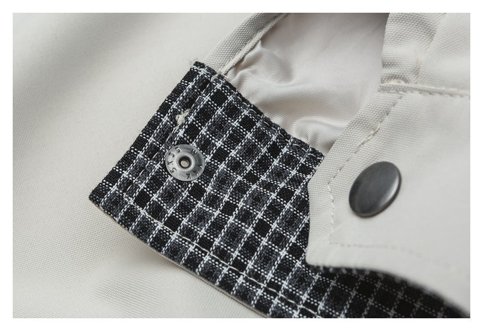 Close-up of a snap fastening on a black-and-white plaid panel beside a light beige garment tab.