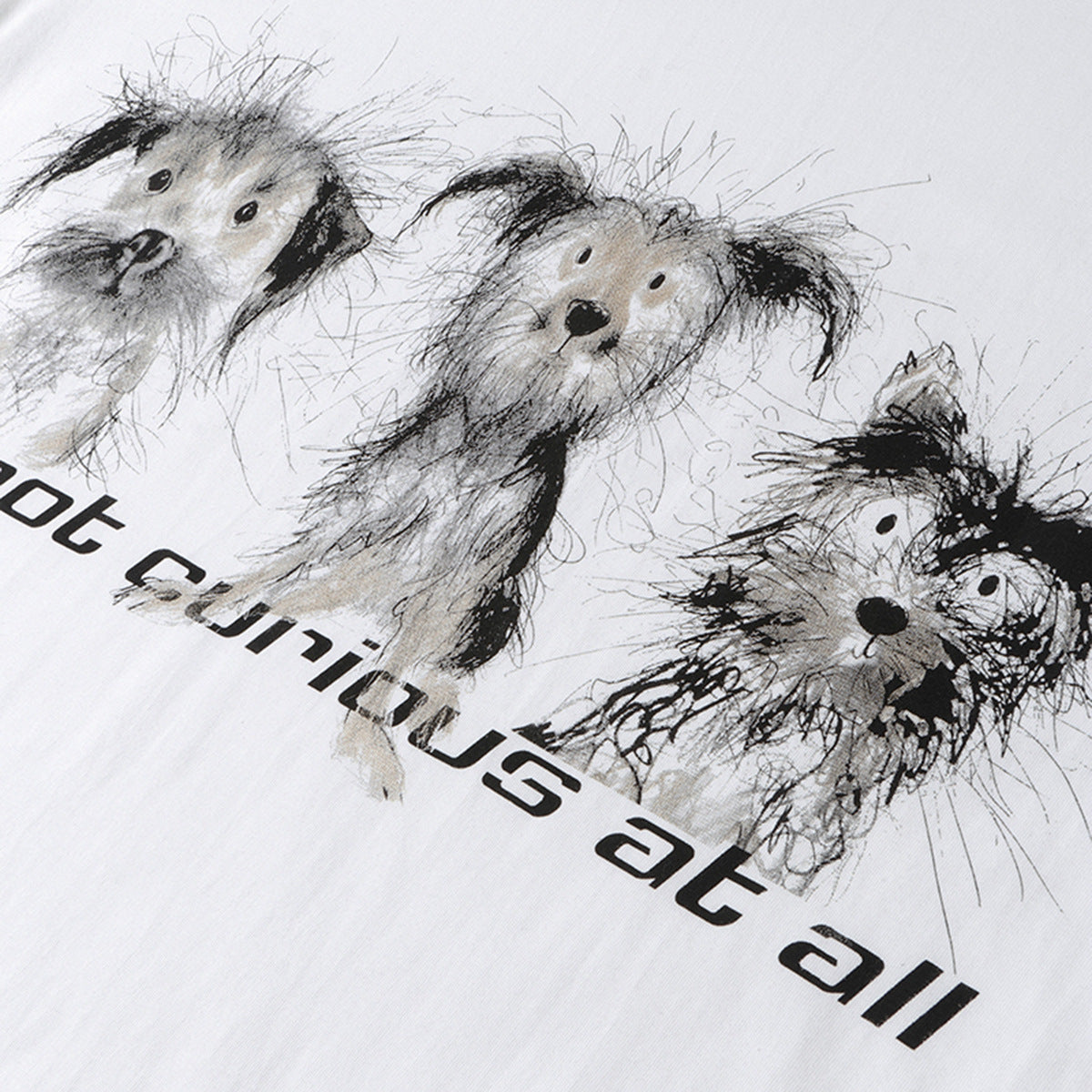Close-up of three sketch-style dogs and black lettering printed on a white T-shirt.