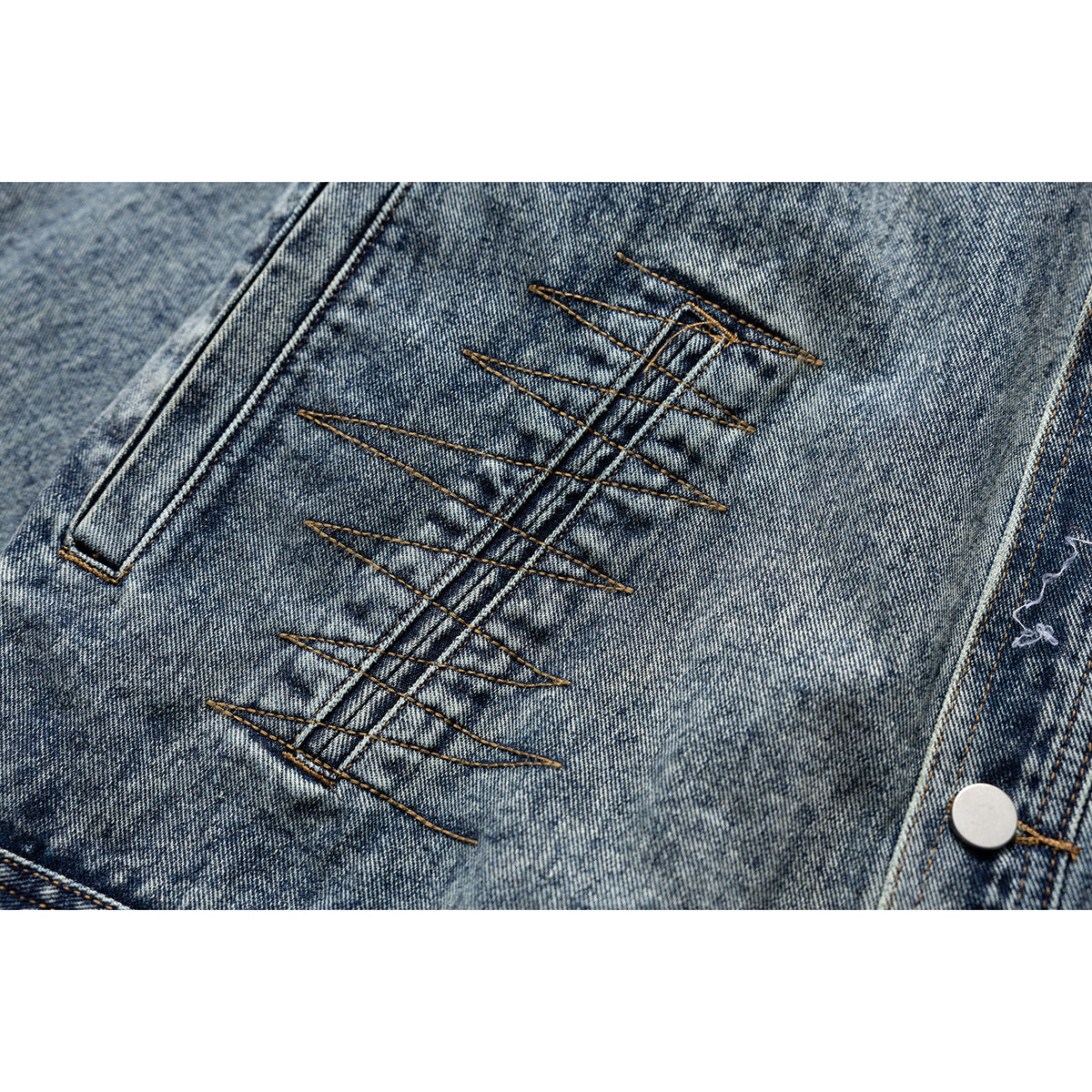 Close-up of a blue acid-wash denim jacket with decorative brown zigzag stitching and a metal snap.