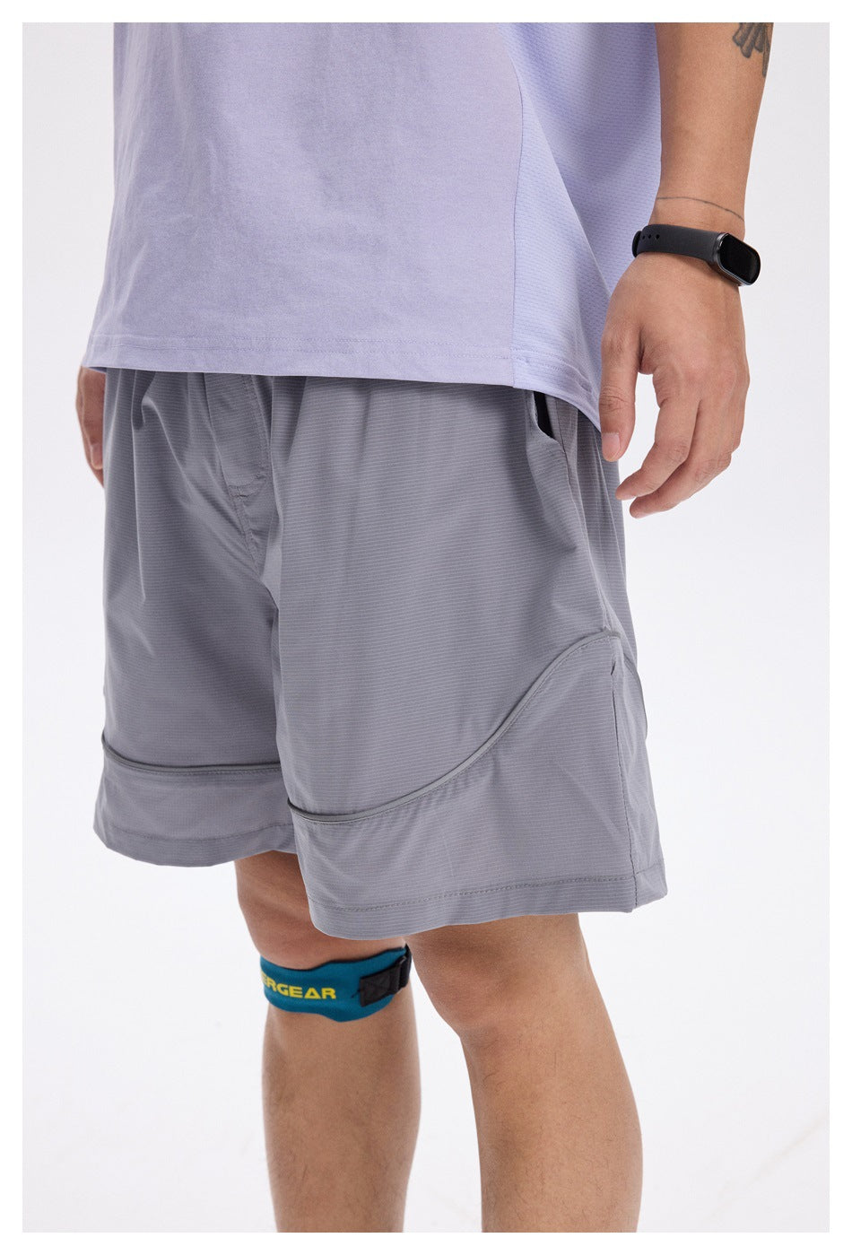 Close view of a person wearing light gray athletic shorts, showing the front, curved panel seams, and hem.