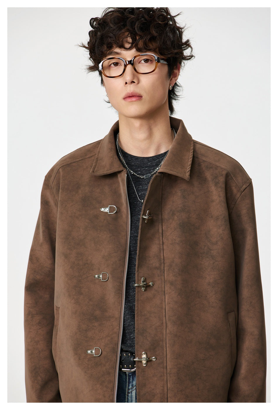 Close view of the brown jacket's collar, mottled surface, zipper, and metal toggle closures.
