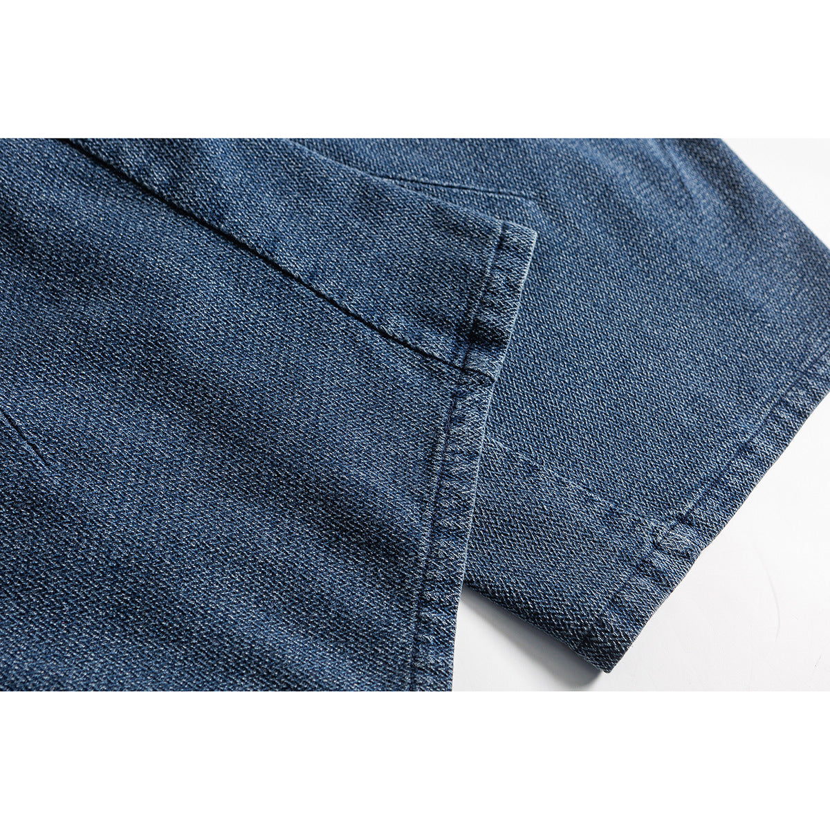 Close-up of blue trouser fabric with a stitched panel seam and folded edge.