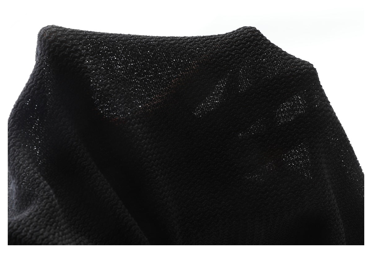 Close-up of the neckline and open knit texture of a black garment.