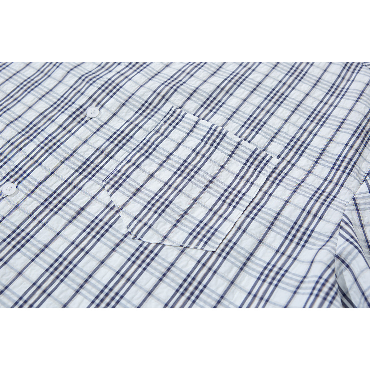 Close-up of the chest pocket and white buttons on a white shirt with blue-gray plaid.
