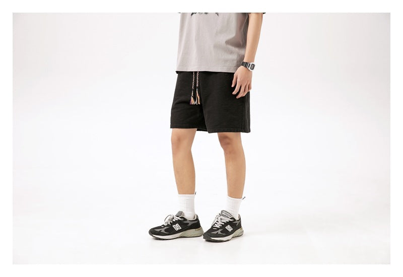 Front view of a model wearing black drawstring shorts, cropped from the torso down.