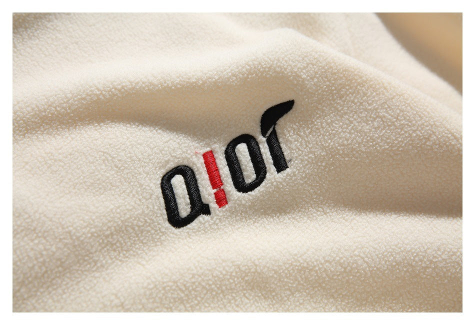 Close-up of black and red embroidered lettering on cream textured fabric.