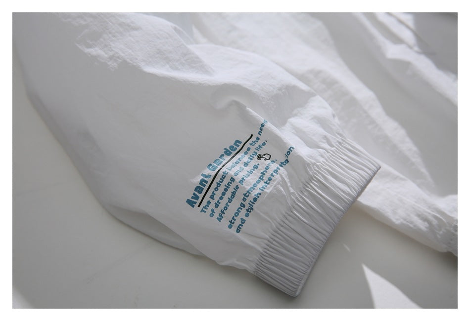 Close-up of the white jacket's elastic cuff with blue English text printed above it.