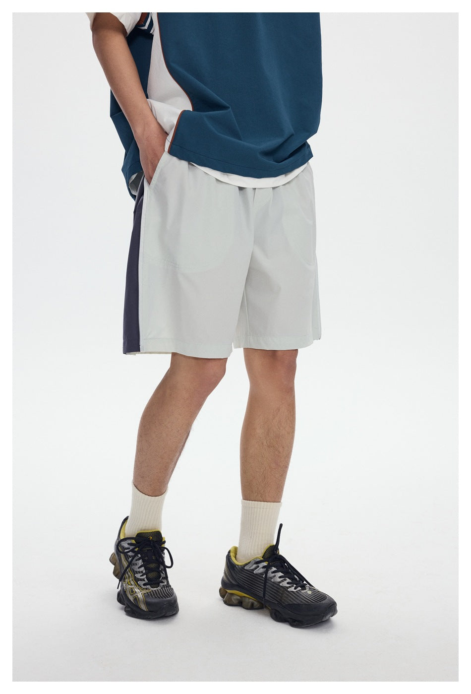 Close view of a model wearing white shorts with a dark side panel, paired with a teal top.
