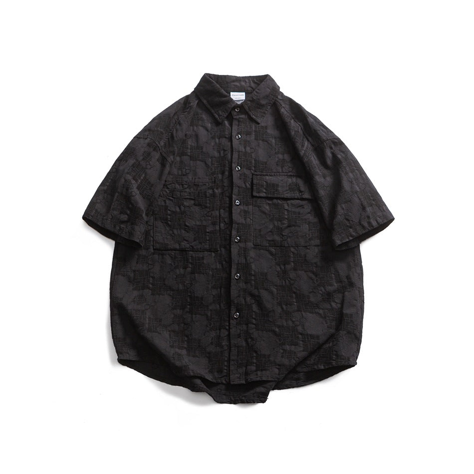 Black short-sleeve button-up shirt with tonal floral jacquard texture and two chest pockets, flat lay front view