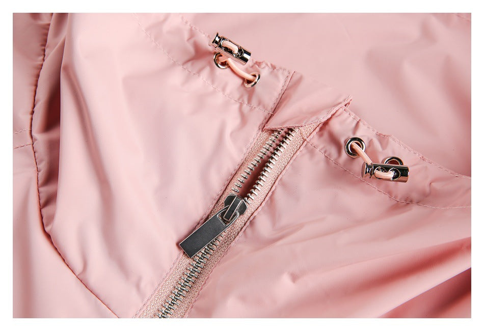 Close-up of a pale pink garment with a diagonal metal zipper and matching drawcord loops with metal fittings.