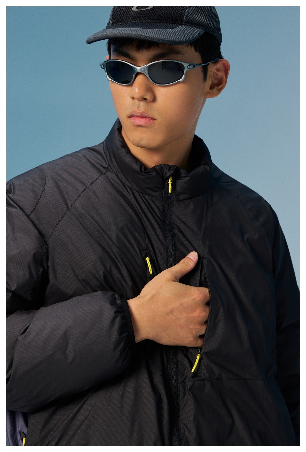 Close-up of a black jacket showing its high collar, front zipper, and yellow zipper pulls.