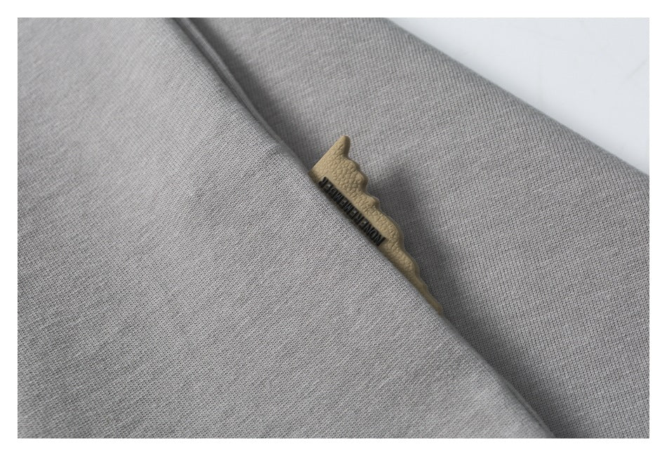 Close-up of gray fabric with a small tan tag bearing dark lettering tucked into a seam.