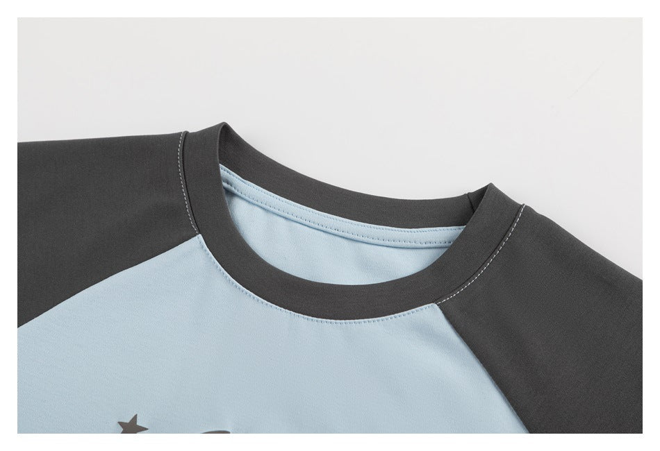 Close-up of a light blue and charcoal raglan T-shirt showing its crew neck and stitching.