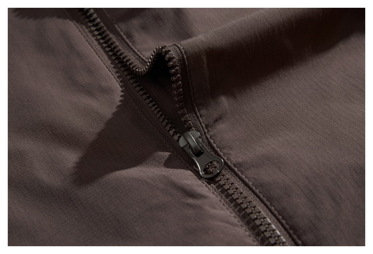 Close-up of a dark brown garment's chunky black zipper and fabric stitching.