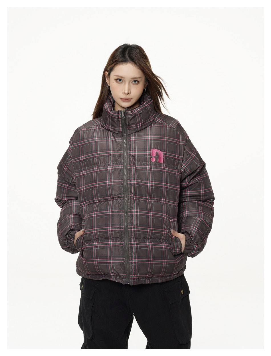 Front view of a model wearing a dark gray plaid puffer jacket with a high collar, front zipper, and pink chest emblem.