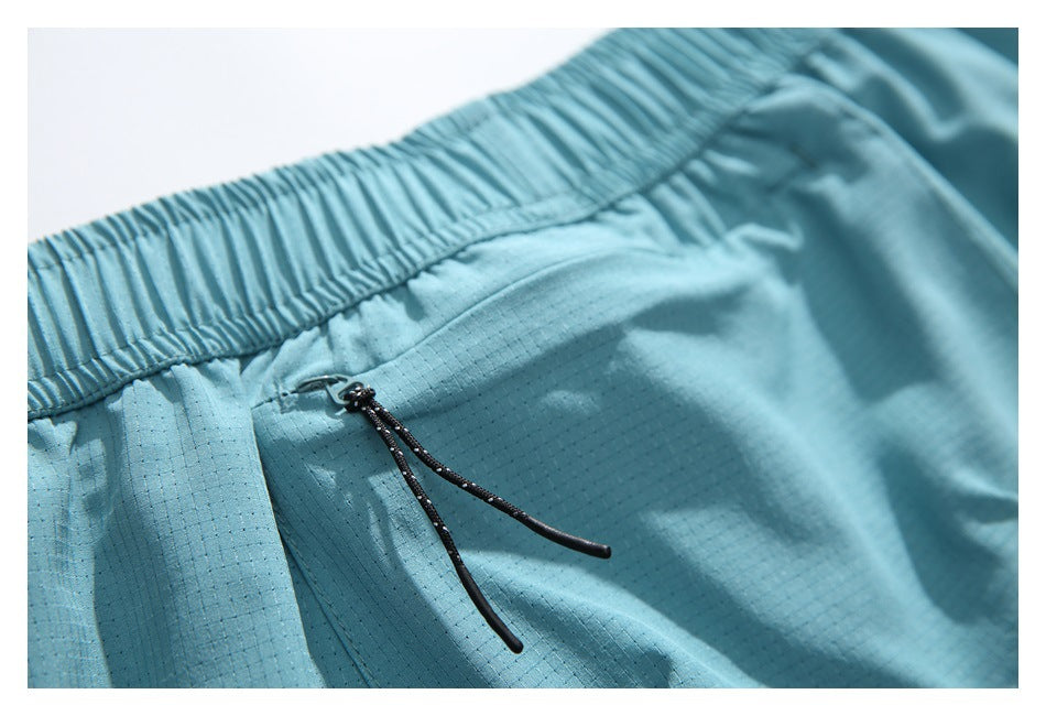 Close-up of the gathered waistband and drawcord zipper pull on aqua shorts.