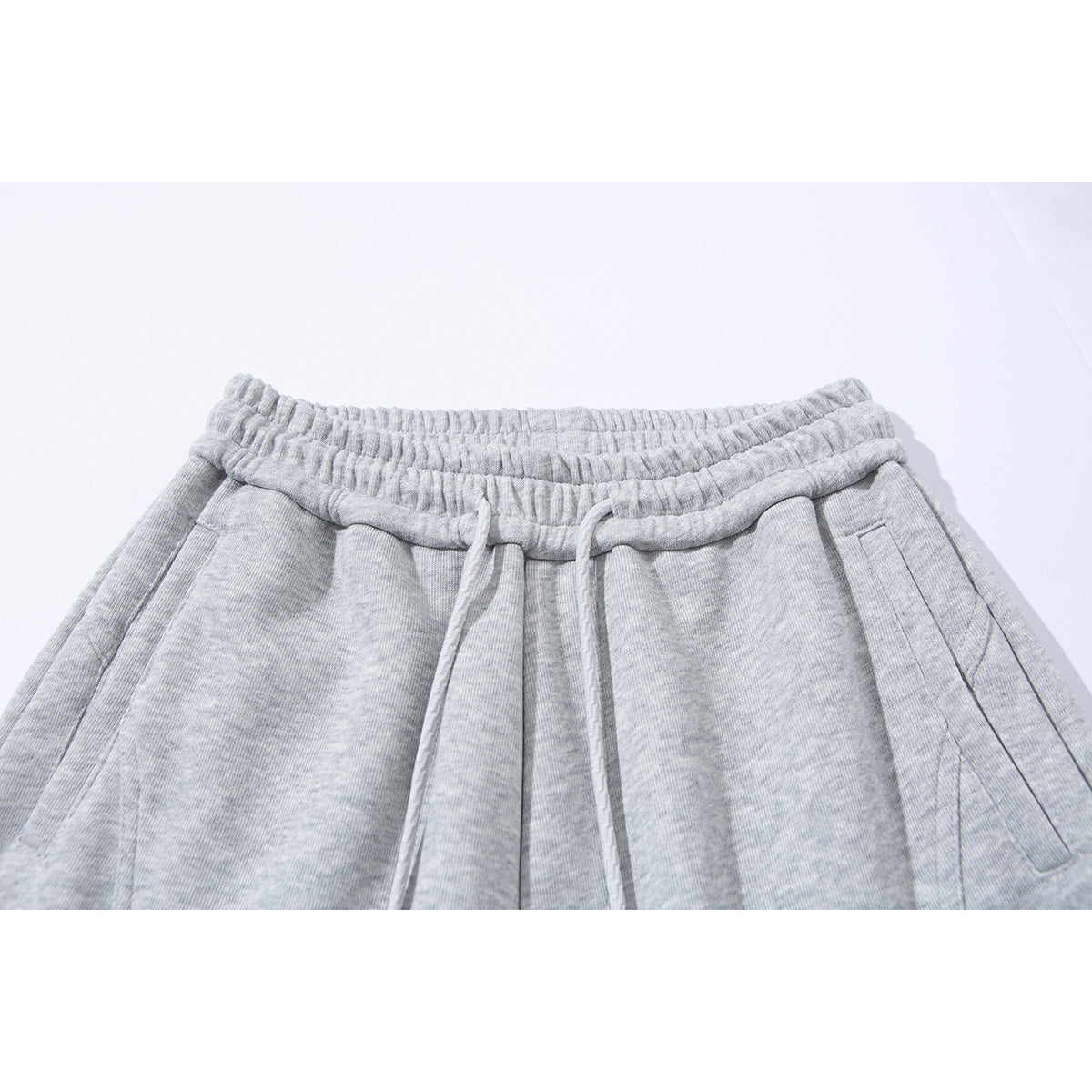 Close-up of light gray pants with an elastic drawstring waist and angled side pockets.