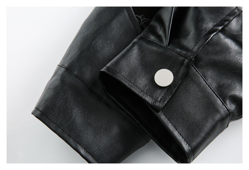 Close-up of a black jacket sleeve cuff with a large round silver-tone snap button.