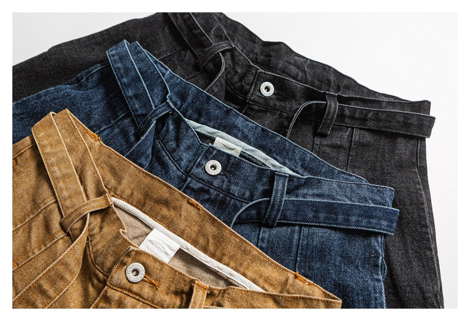 Three pairs of trousers in tan, dark blue, and black arranged together, showing their waistbands and belt loops.