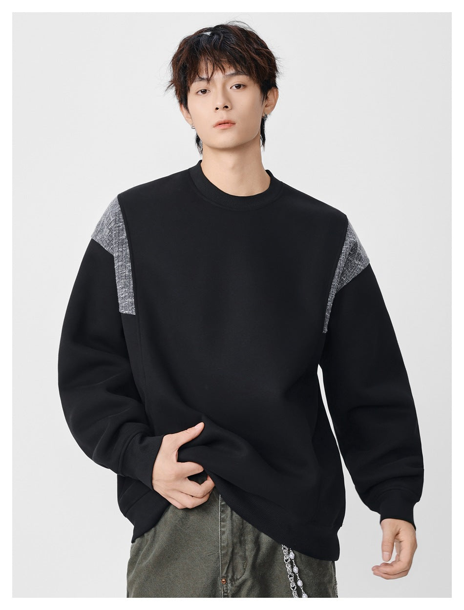 Front view of a model wearing a black crewneck sweatshirt with gray textured shoulder panels.