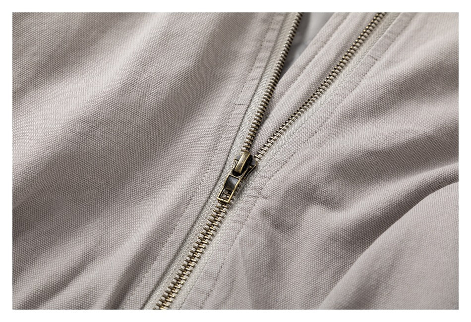 Close-up of the antique-brass zipper on a light taupe jacket.