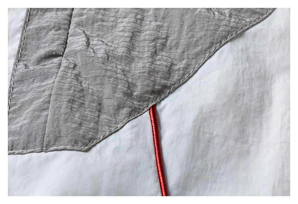 Close-up of gray quilted fabric with horizontal stitching and a red cord along the edge.